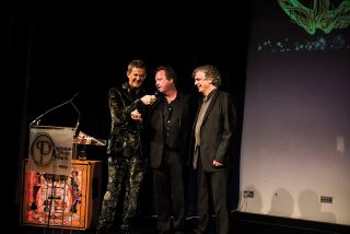 Mark King (centre), the worst-dressed man of 1989, picks up his Outer Limits gong from Matthew Wright, the worst-dressed man of 2017