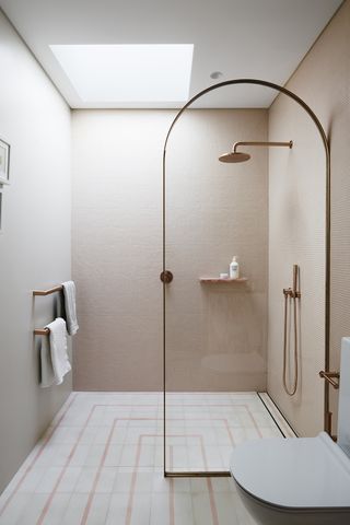 Minimal bathroom with arched shower screen and pale pink walls