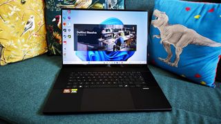 A black ASUS ProArt P16 laptop on a green sofa