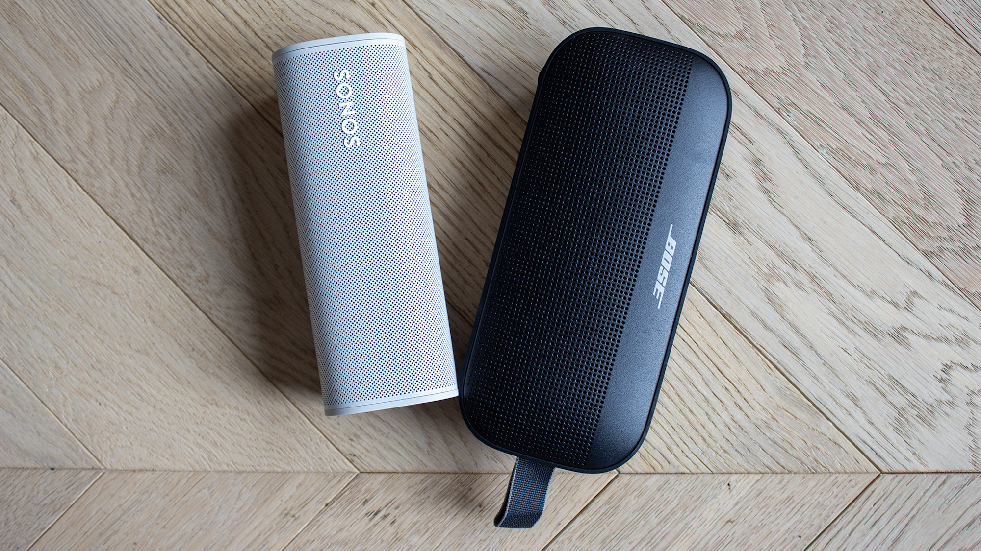 A side-by-side view of a white Sonos Roam 2 and a black Bose SoundLink Flex.