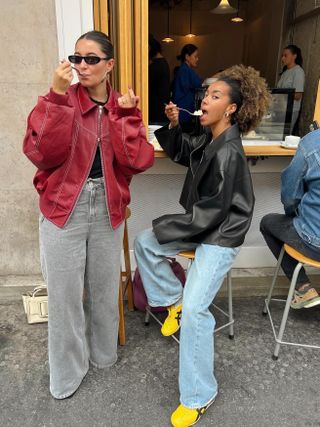 Fashion influencer Amaka Hamelijnck and her friend wearing chic fall outfits with jeans and leather jackets.