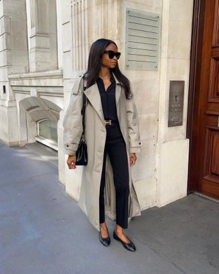 Lorna wears a trench coat, black shirt, tailored trousers and ballet flats
