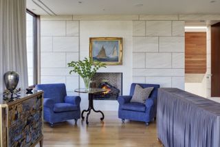 A living room with blue armchairs either side of a nautical print