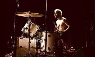 Riz Ahmed sitting at a drumkit in Sound of Metal