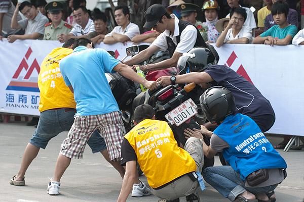 How many marshalls does it take to hold a motor-bike up? Tour marshalls earn their keep prior to the final stage in Dangfong.