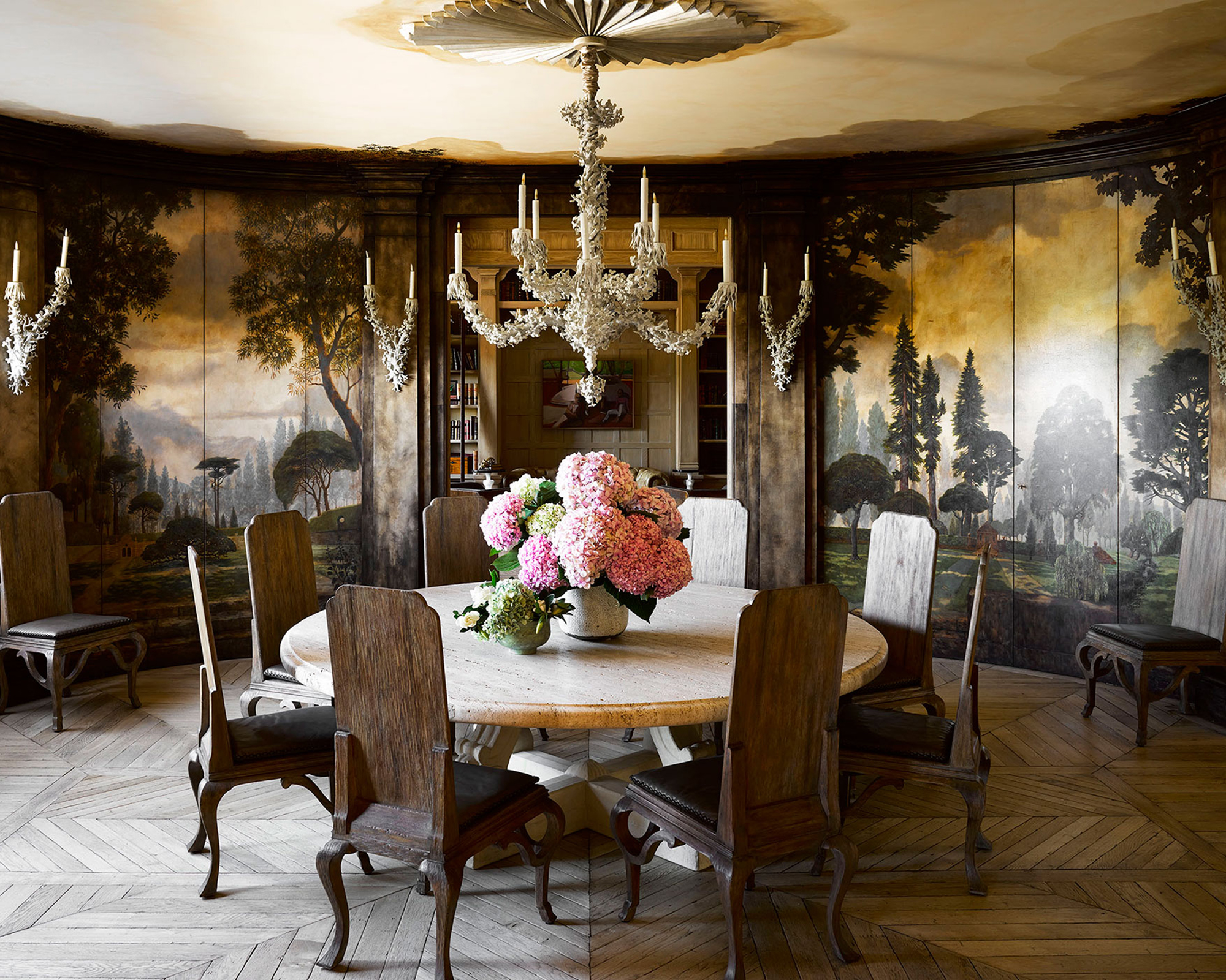 dining room with round wood table and wood chairs and a forest mural on the walls