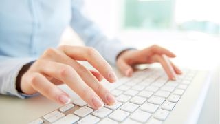 Person using both hands to type on a white chiclet keyboard