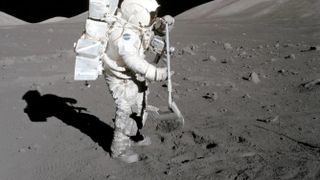 apollo astronaut on the moon with a rake. to the side of him is his shadow. in the back are low hills. moon dust covers his boots and lower legs