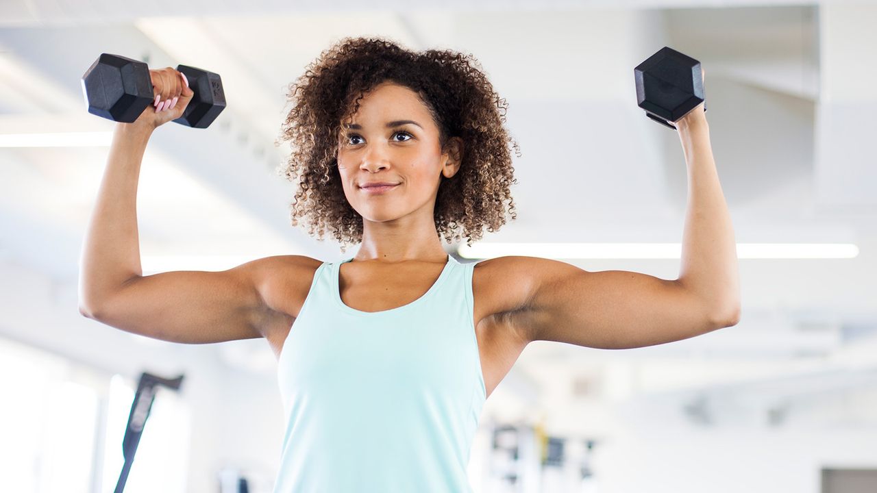 A woman with strong, muscular arms doing a dumbbell arms workout