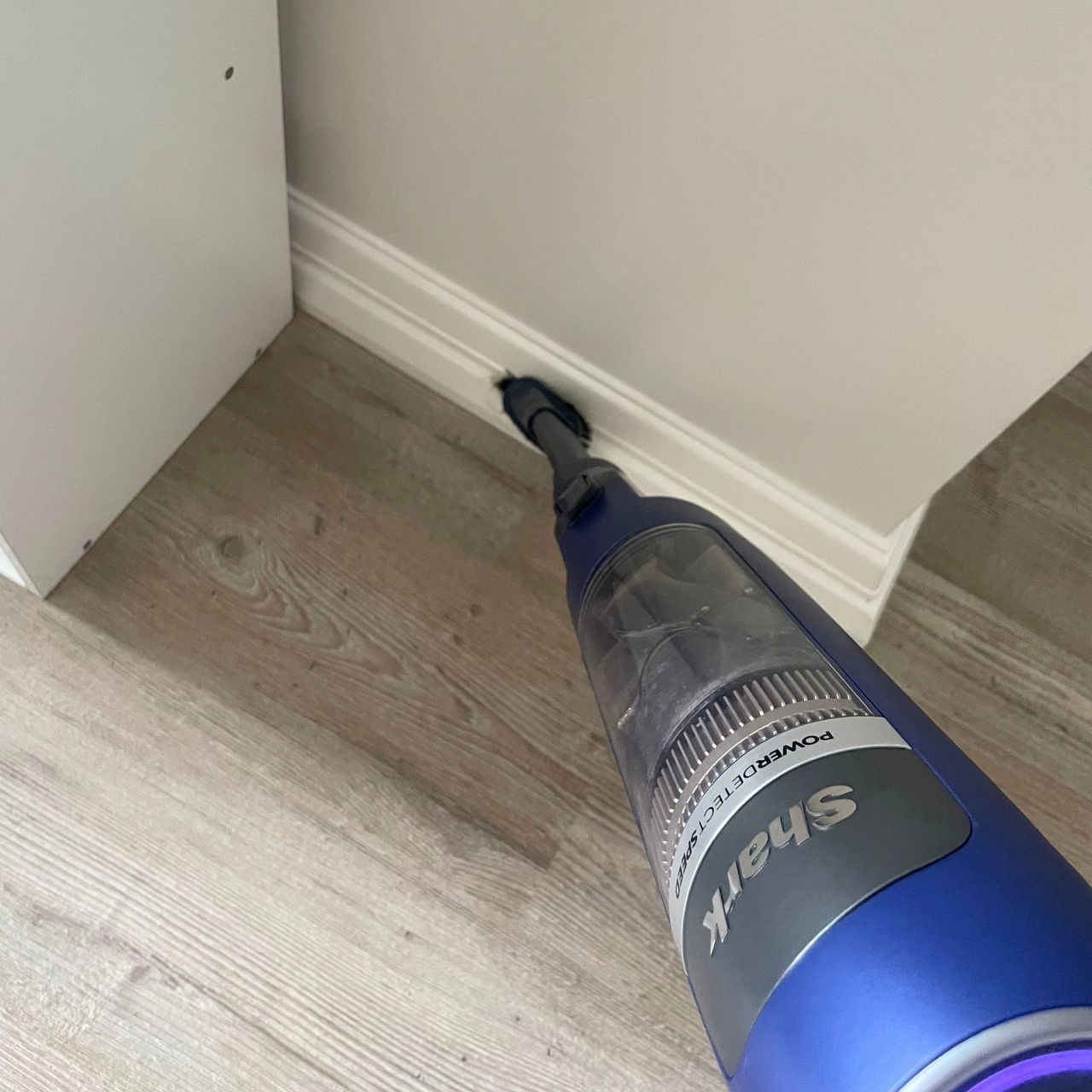 Using a Shark vacuum to dust white skirting boards
