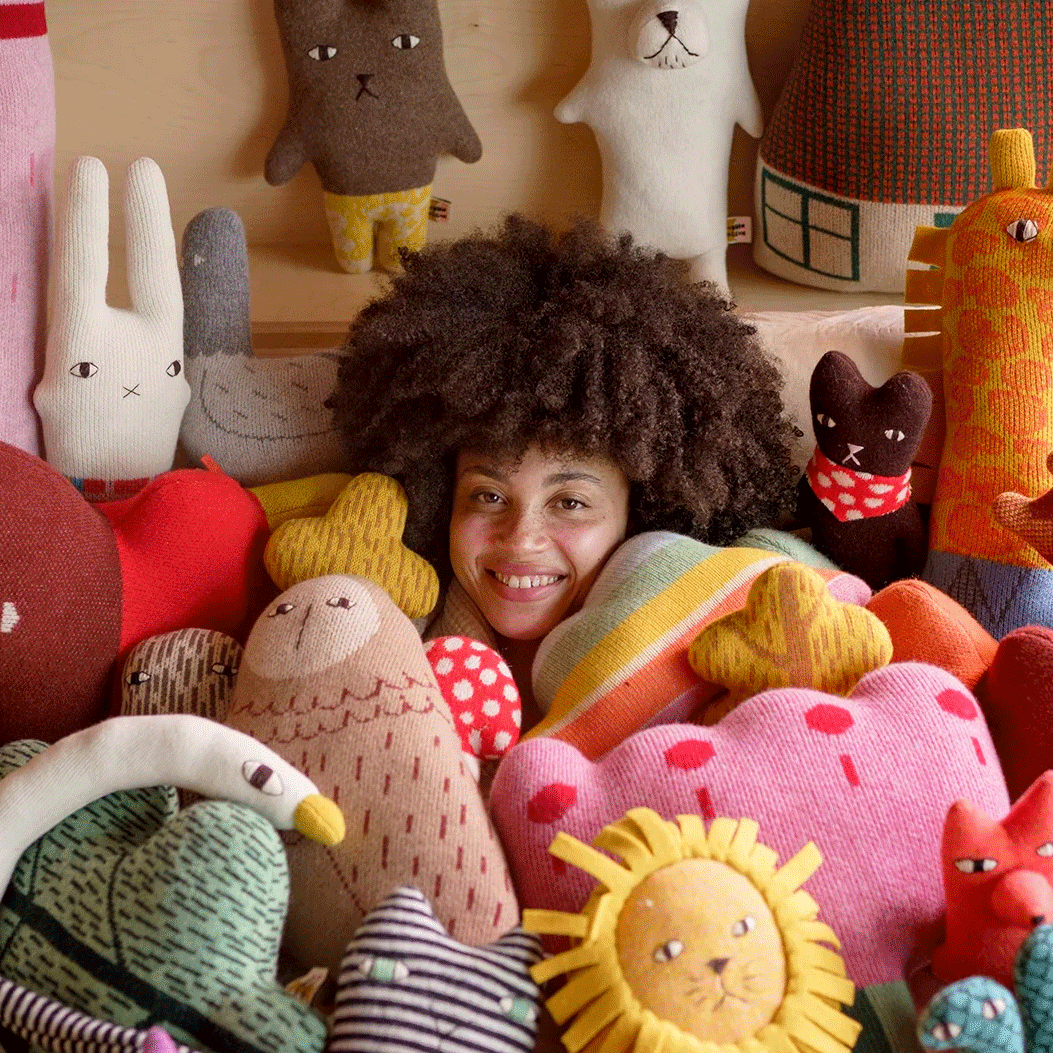 Woman with head poking out among large pile of cuddly toys