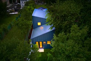 Hem House. An overview photo of a blue house at night under green trees.