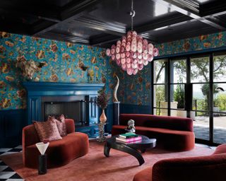 maximalist living room with blue patterned wallpaper, red rug and red sofa