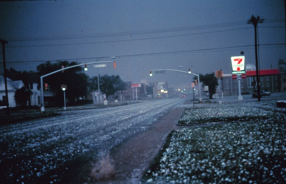 Large hail collects on streets and grass during severe thunderstorm. Larger stones appear to be nearly 2 to 3 inches in diameter. 