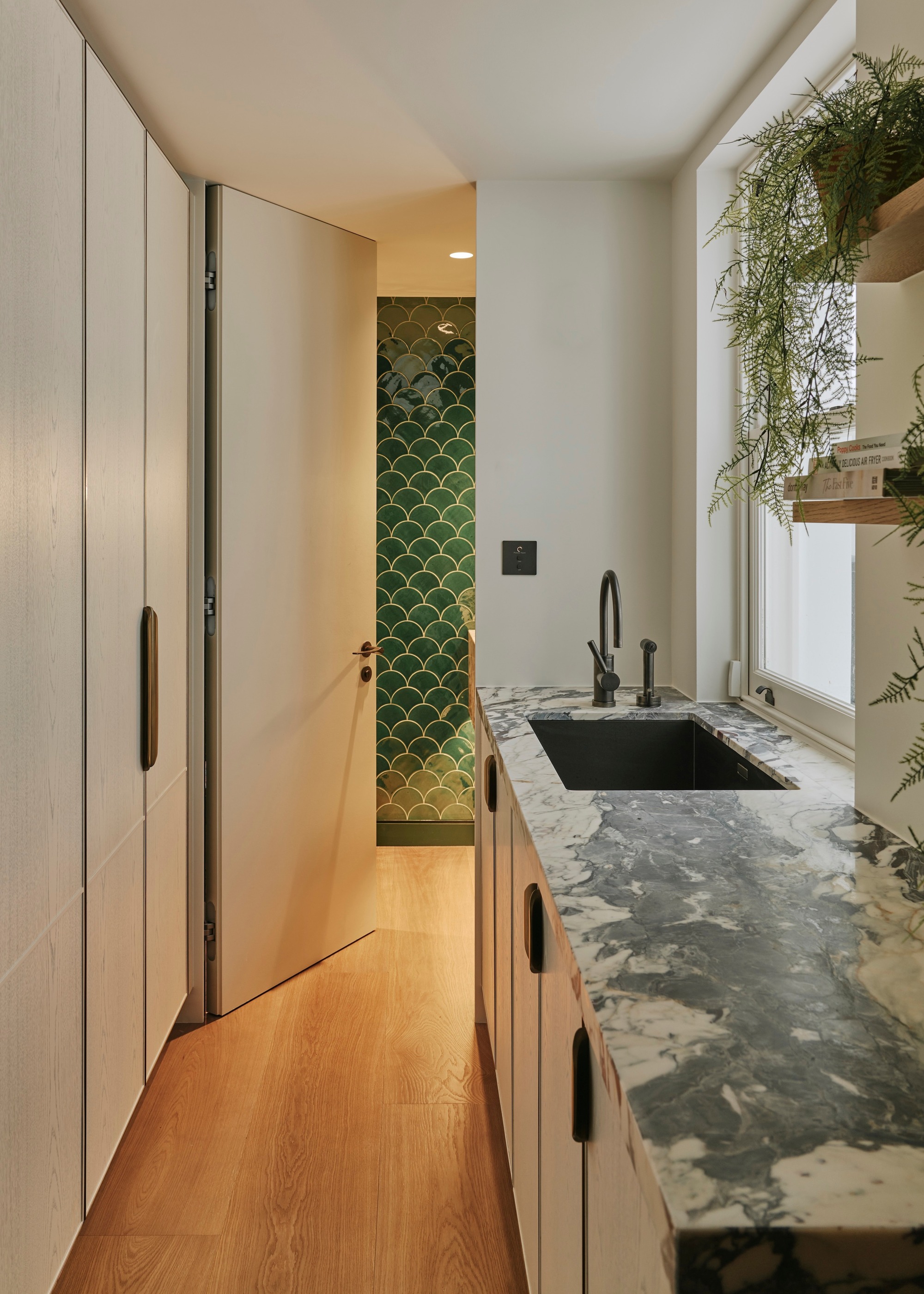 utility room with timber floor and door open to reveal green fish-scale wall tiles