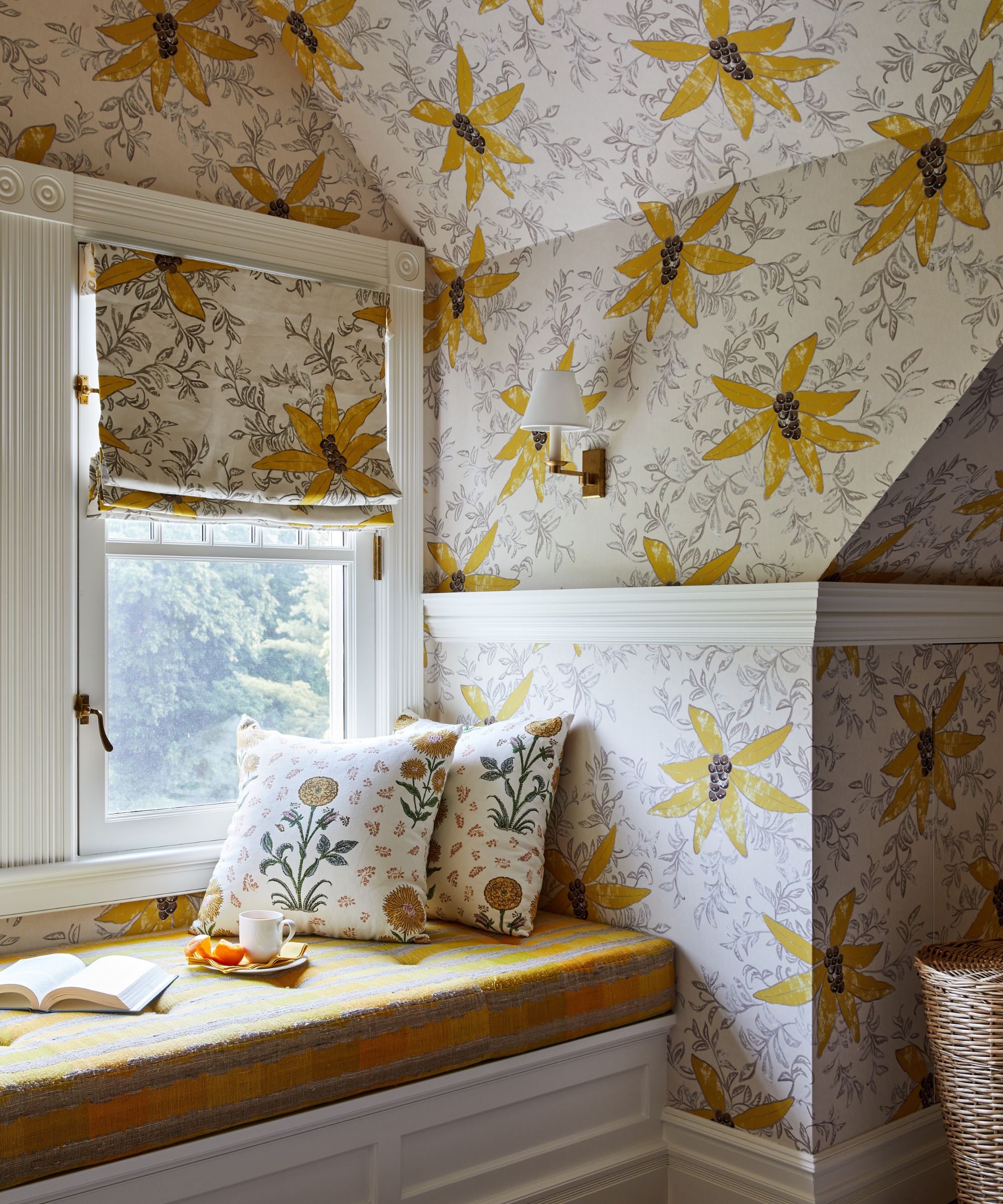 Window seat with yellow floral wallpaper, built-in bench with yellow plaid cushion, floral throw pillows, and a matching blind