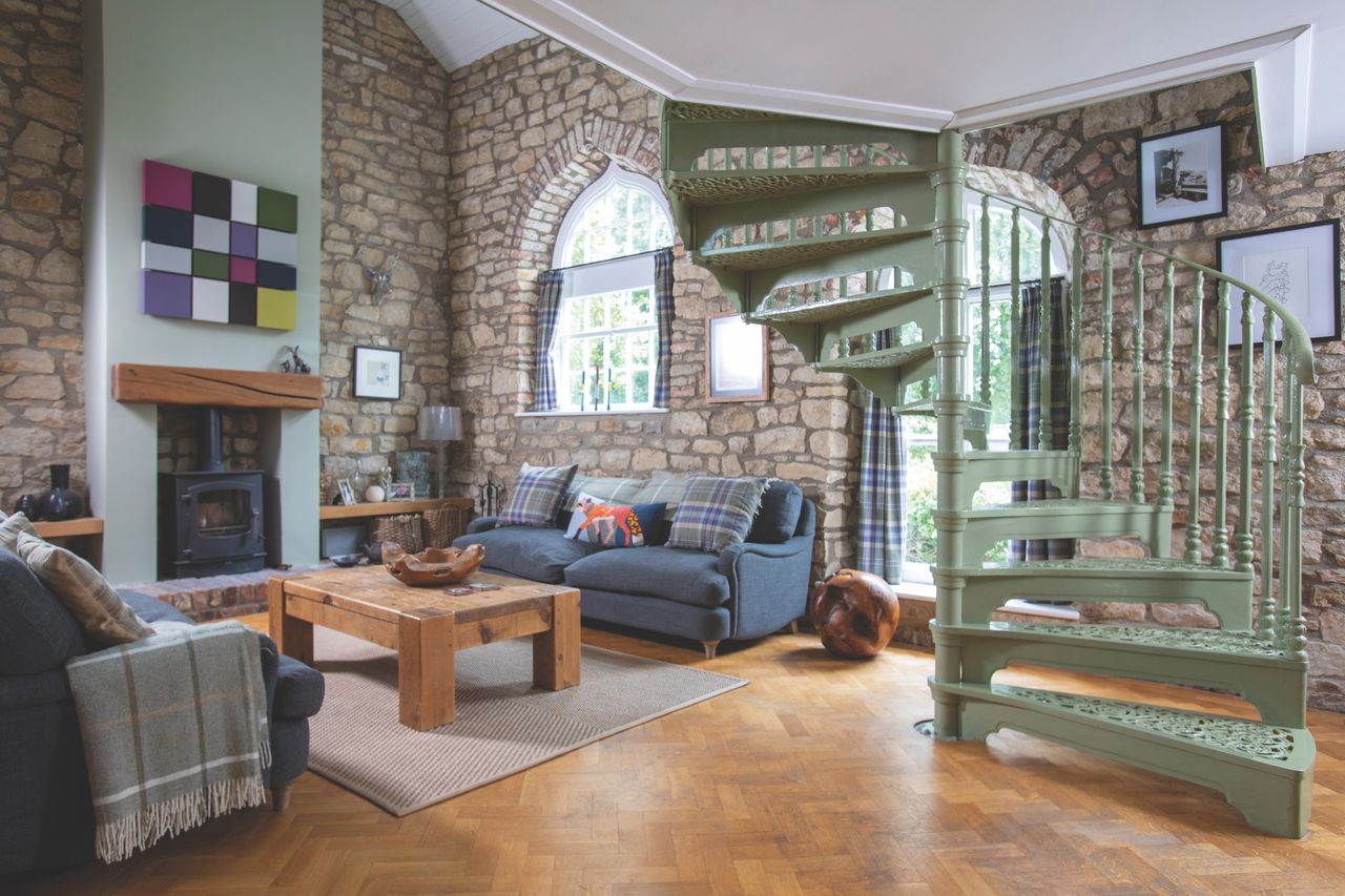 Original stone walls left exposed in the sitting room inspired the build materials in the extension. The stunning spiral staircase was restored and painted in a sage green to rejuvenate the interiors.