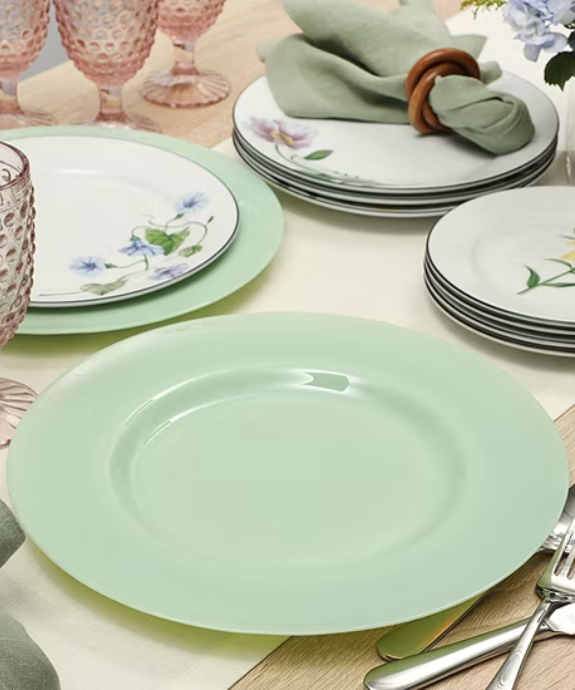 Table with jadeite charger plates, white floral dinner plates, and pink Jupiter goblets