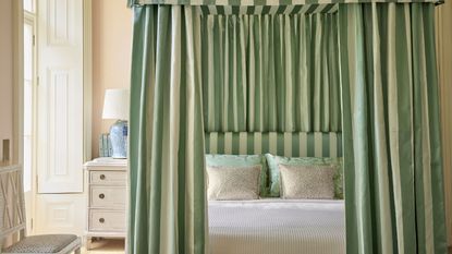 Cream bedroom with four-poster frame and striped green and cream curtains, and matching headboard