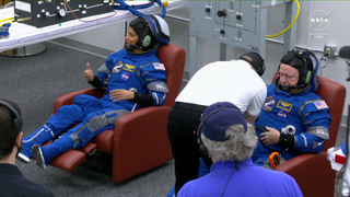 Two astronauts suit up in blue spacesuits for Boeing's Starliner Crewed Flight Test launch.