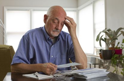 Older man looking frustrated while reviewing bills