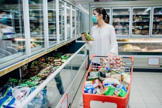 A woman wearing a face mask while shopping at the grocery store.