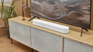 Sonos Beam Gen 2 in white on a modern wooden media unit sitting below a TV