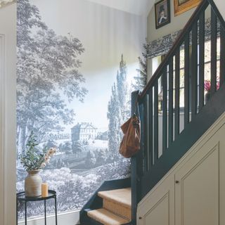 A staircase with a large wall mural of a countryside sceneryassignmen