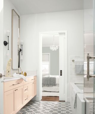 An ensuite with light pink cabinets and a gray and white floor