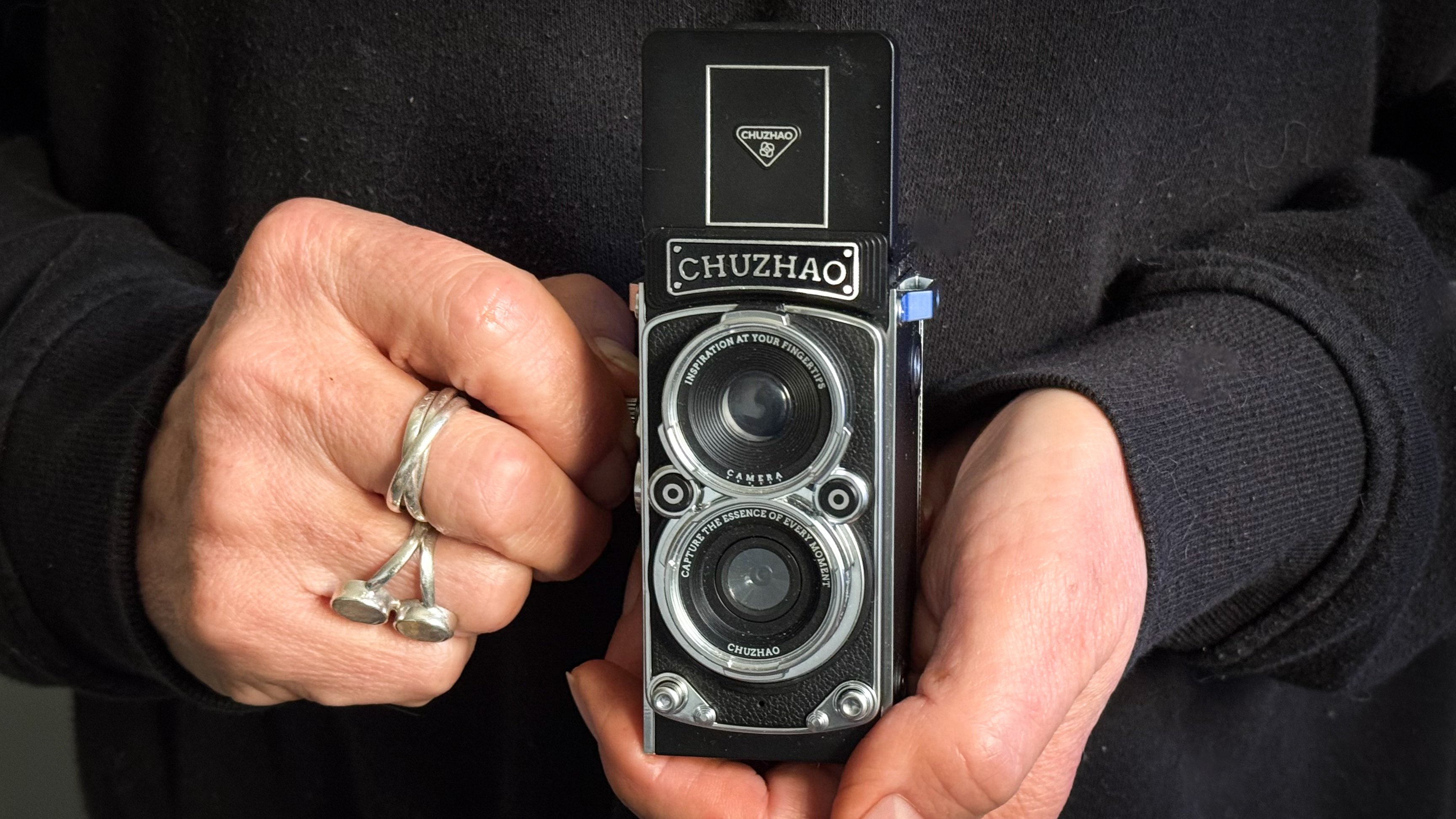 Chuzhao Digital Camera being held in a woman's hands against her black jumper
