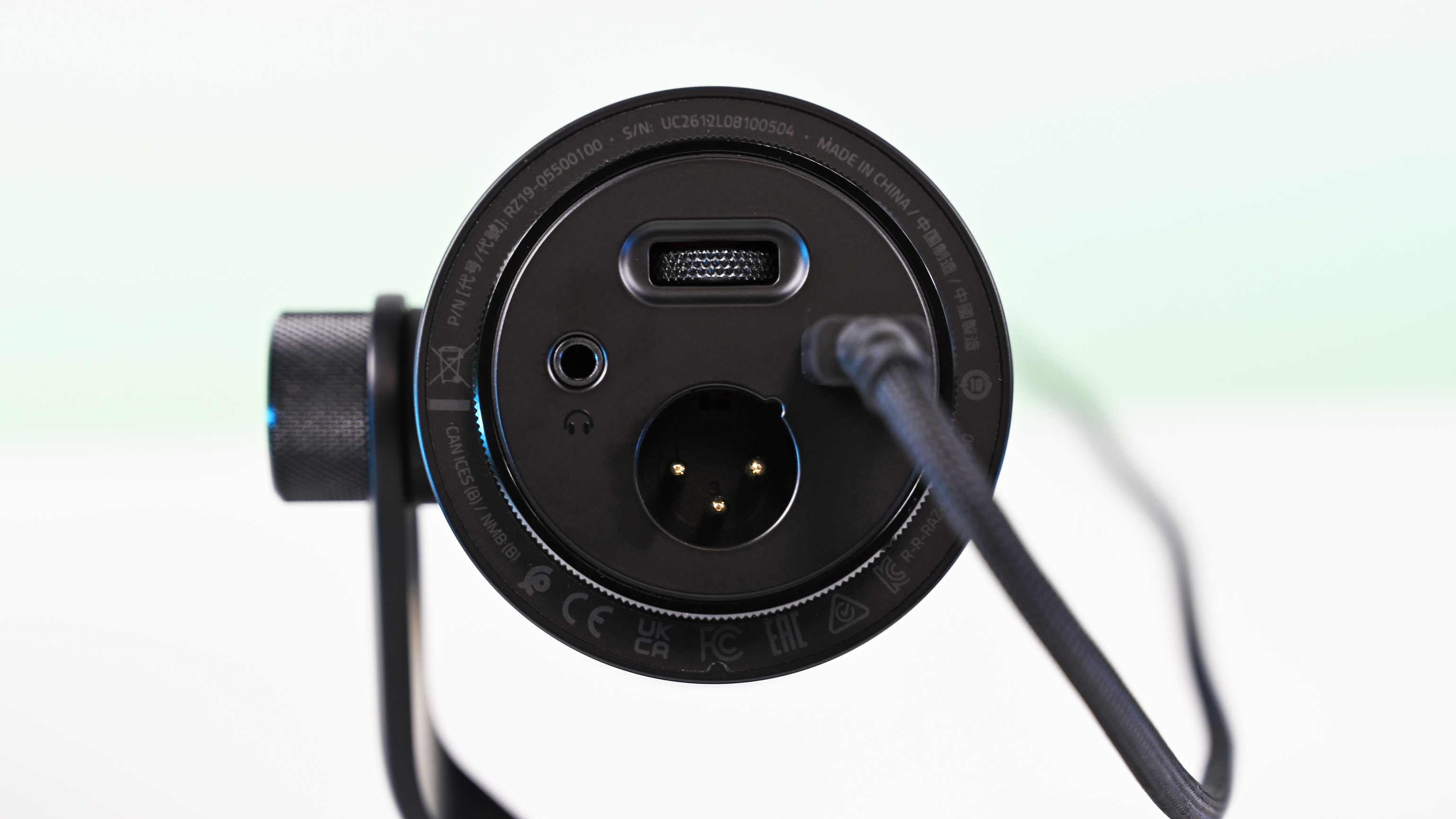 Bottom view of the Razer Seiren V3 Pro microphone showing the circular base with a headphone jack, XLR port, USB-C cable plug, and gain wheel.