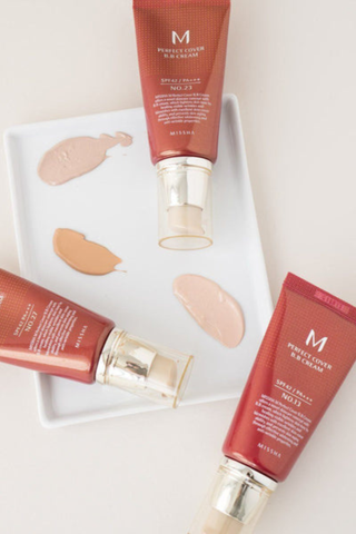 bottles of Missha sunscreen with swatches of three different shades