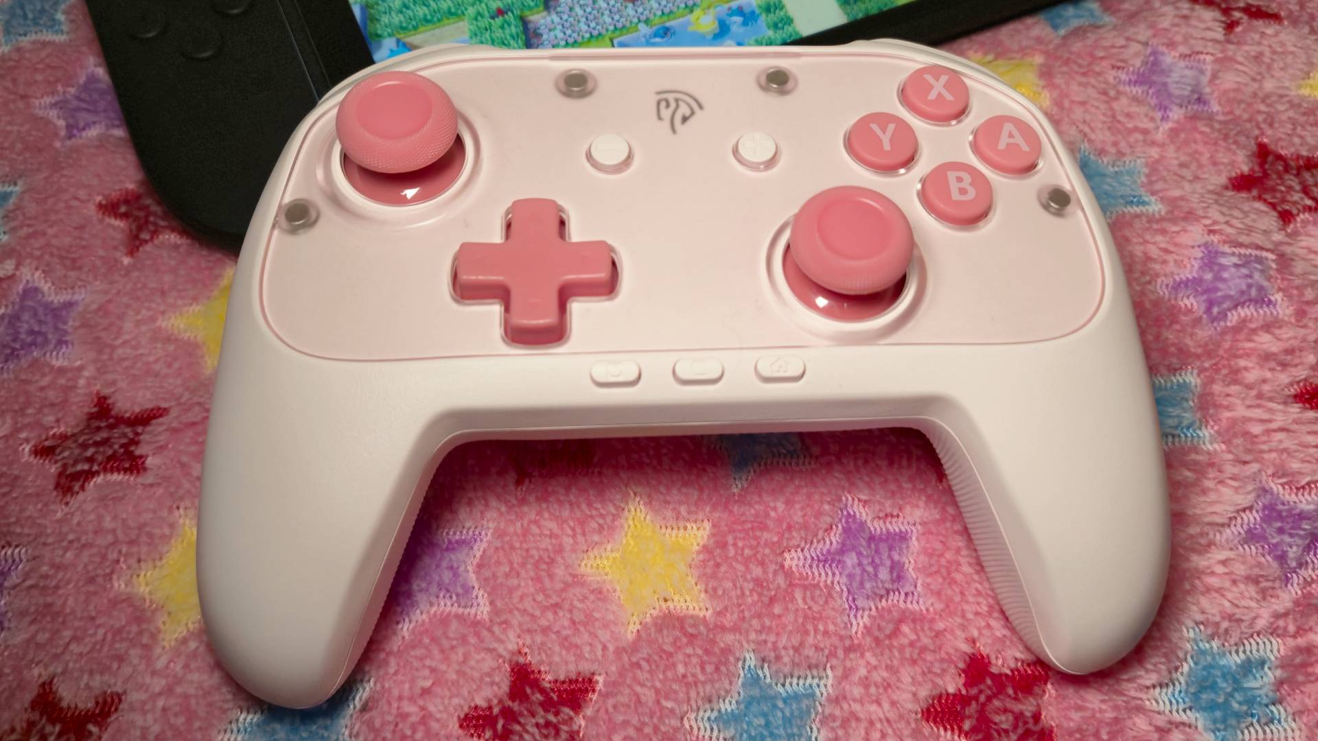 Photo of the EasySMX S10 Lite controller in pink sitting on a pink starry blanket.