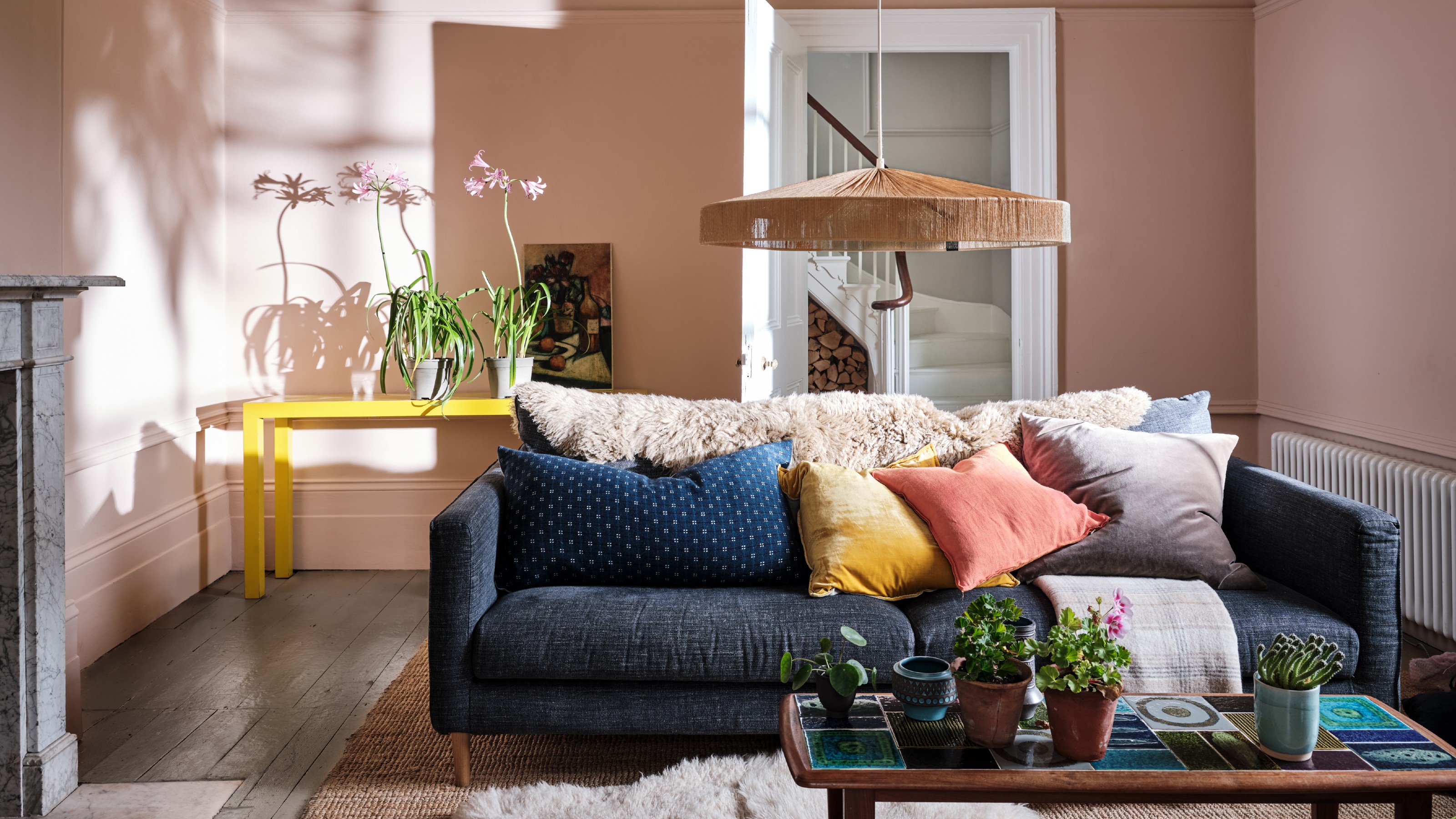 A living room painted in Farrow & Ball's Setting Plaster shade with a navy sofa