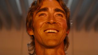 Lee Pace smiles while bathed in orange light in Foundation.