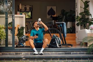 Images shows cyclist rehydrating after an indoor training session on a turbo trainer