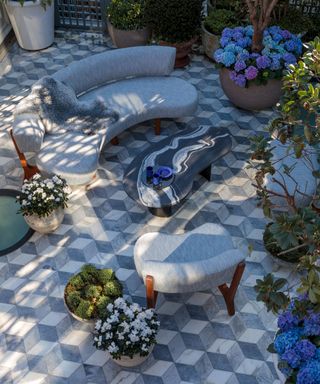 Geometric tiles, potted plants and curved outdoor sofas show how to make a small garden look bigger.