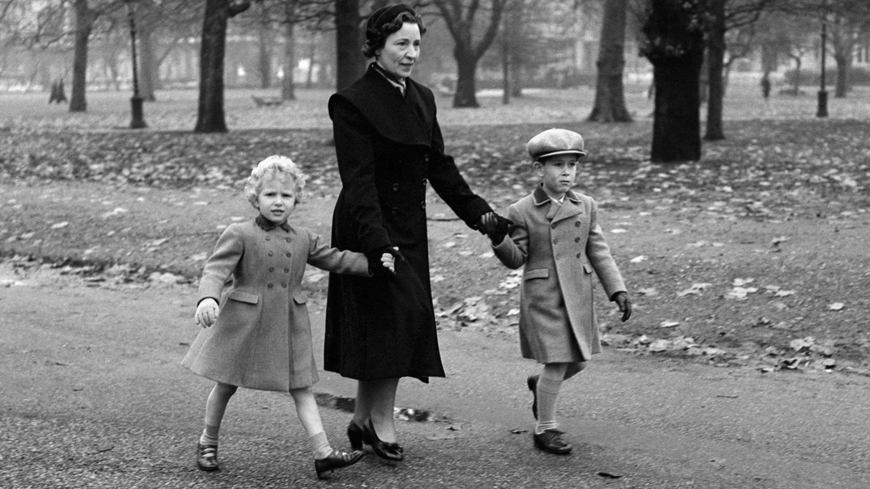Princess Anne and King Charles walk through Green Park with their Governess on their return to Buckingham Palace