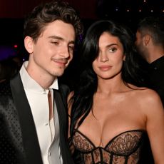 Timothee Chalamet and Kylie Jenner stand together at the 2025 Oscars after party where Kylie wears a lacy corset dress