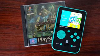 Super Pocket sitting on woodgrain table next to Legacy of Kain: Soul Reaver for PS1