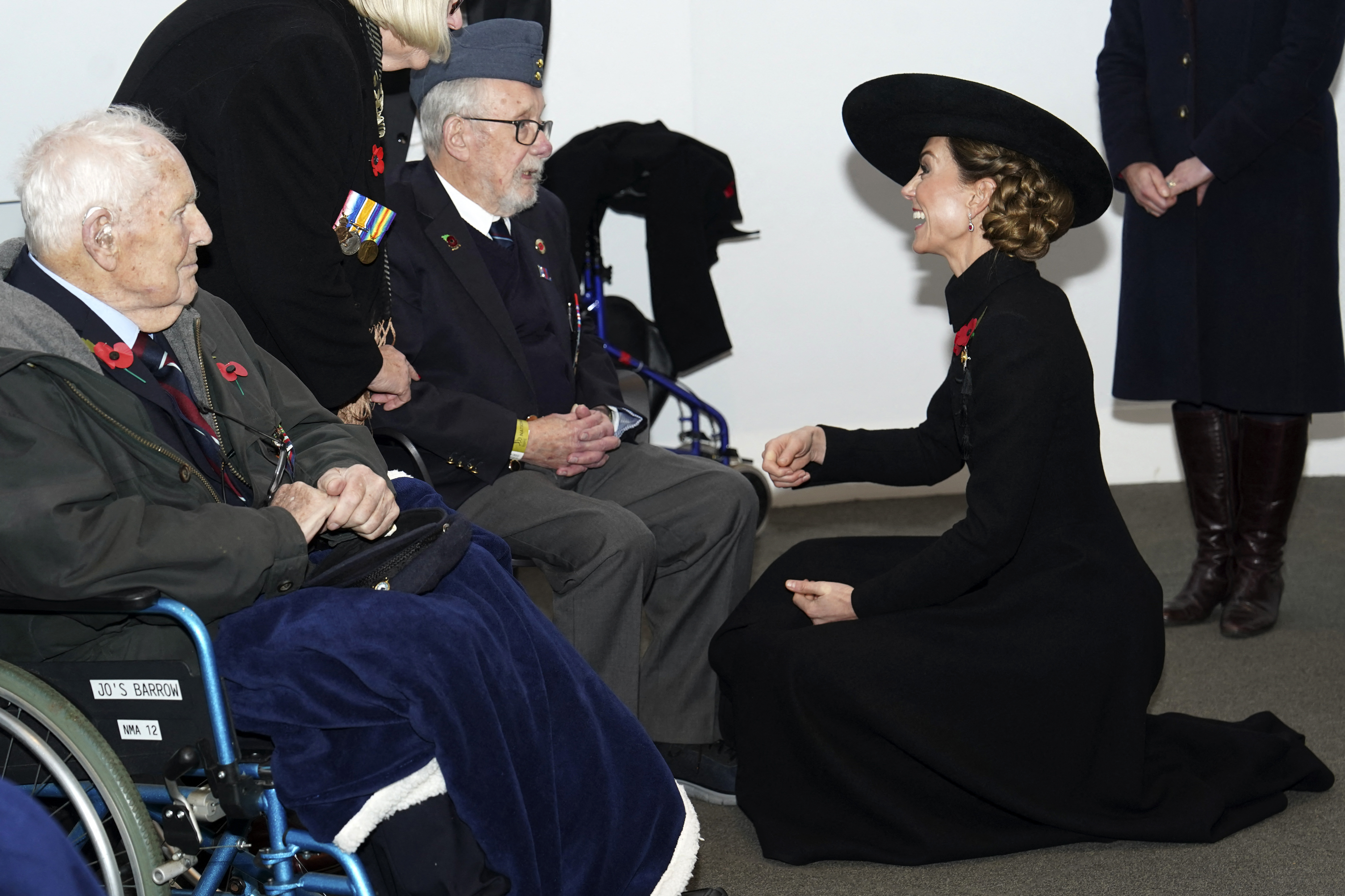 Kate Middleton kneeling down and talking to veterans in wheelchairs