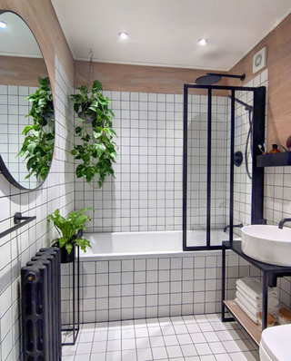 Bathroom with white tiling and Crittal-style shower screen, matt black radiator and round mirror