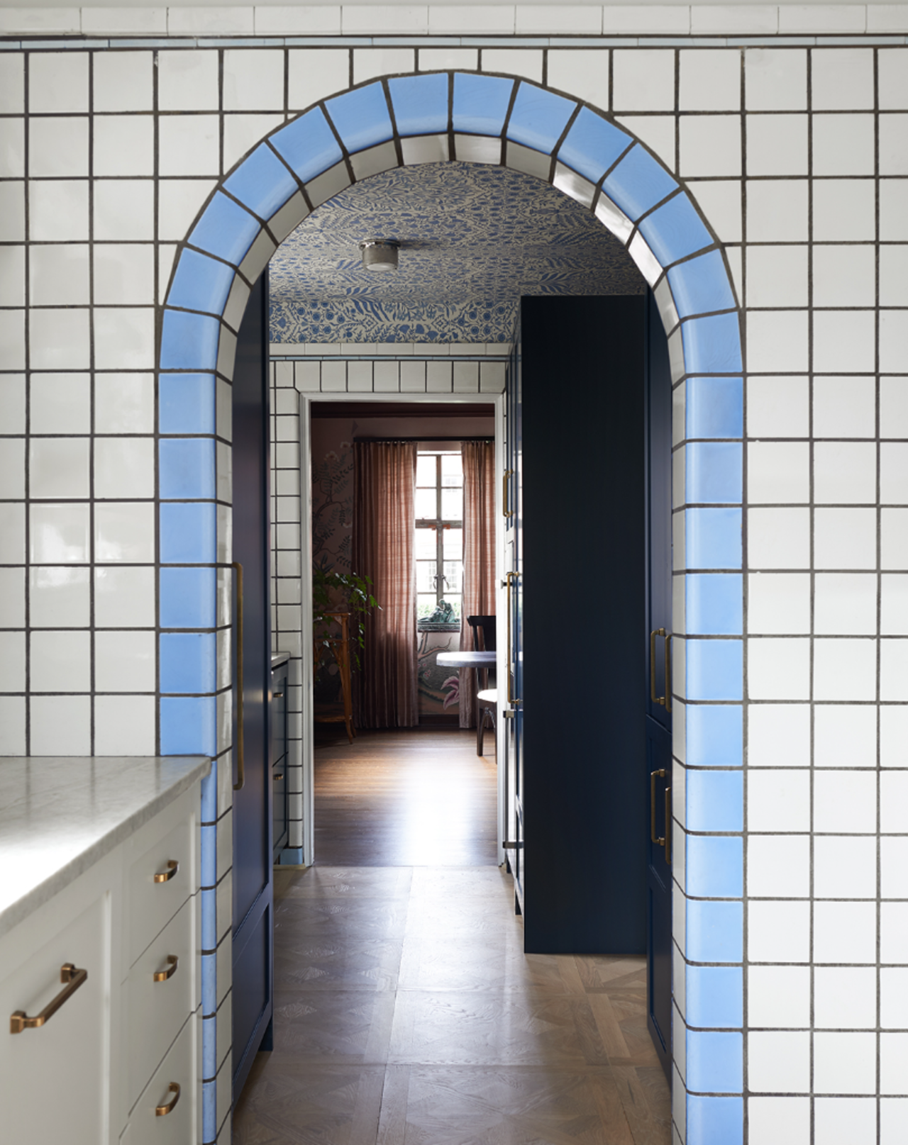 Image of a kitchen doorway. The walls are a white tile and the door reveal is a light blue tile.