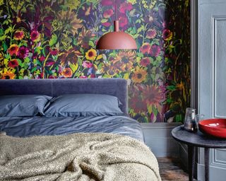 bedroom with floral wallpaper, blue bed and duvet cover and red low hanging pendant light