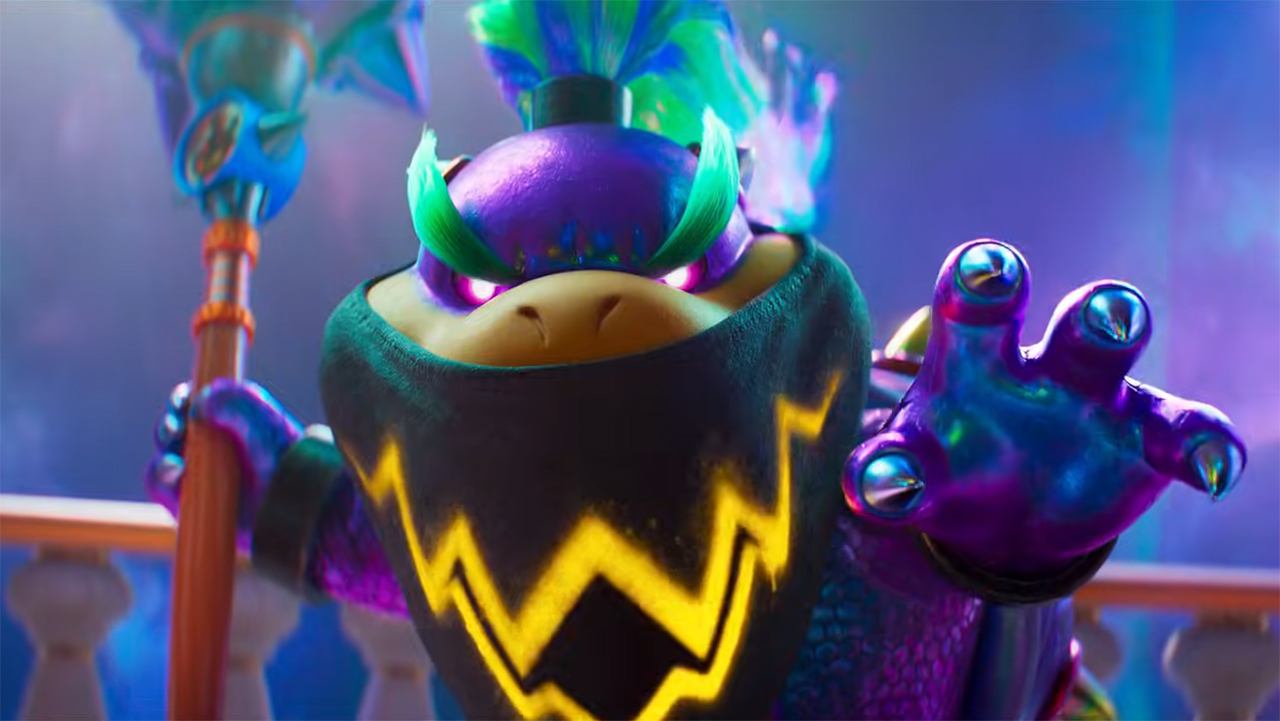 A close up of Bowser Jr wearing a neckerchief, holding his left hand out, and holding a paintbrush in his right hand in The Super Mario Galaxy Movie