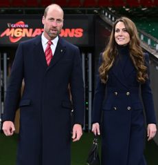 Kate Middleton and Prince William walking on to a rugby pitch smiling in March 2025