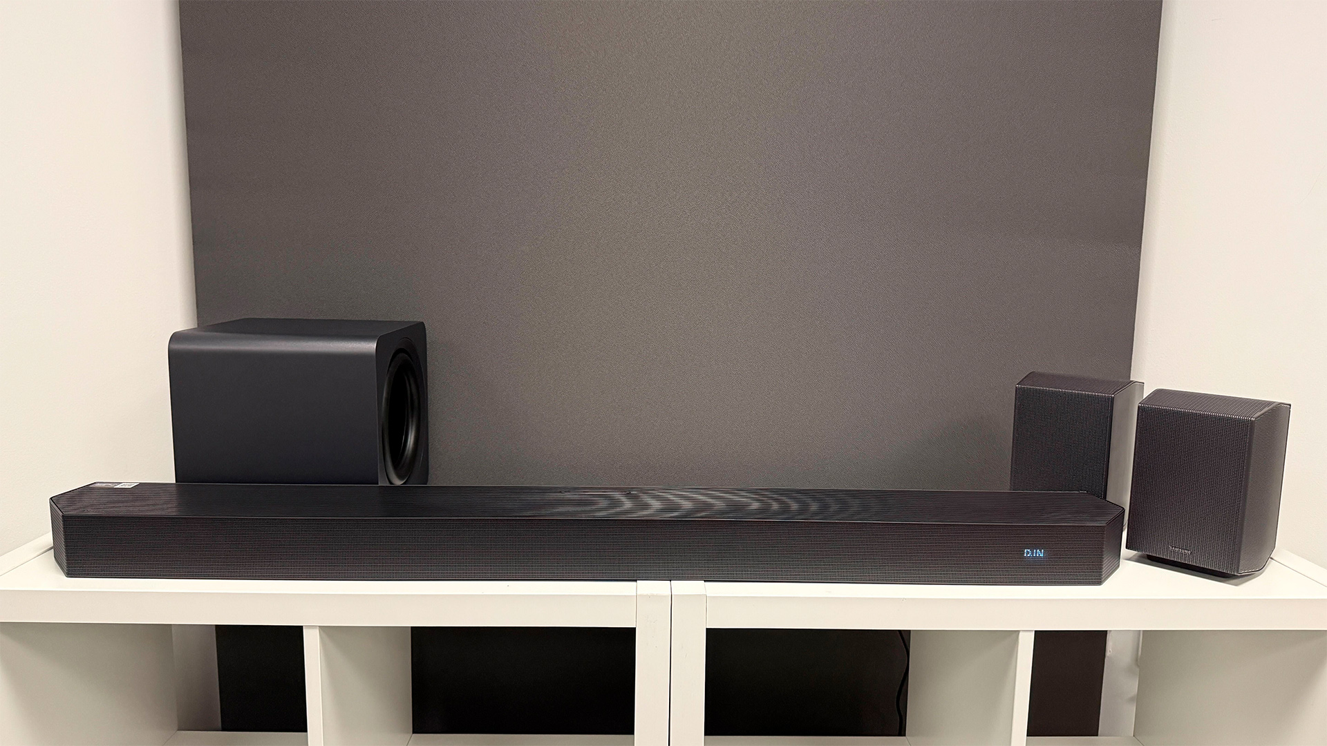 Samsung HW-Q990H soundbar package on white wooden shelf unit in front of grey baffle in test room