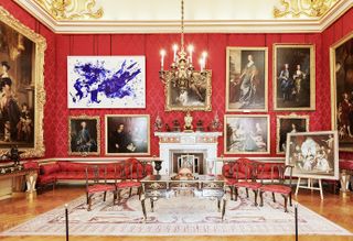 Classical interior of palace with portraits on wall but one abstract blue framed piece of art