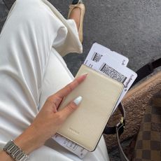 woman holding cream-colored passport holder