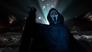 Ghostface stands with its knife raised in a theater in Scream VI.